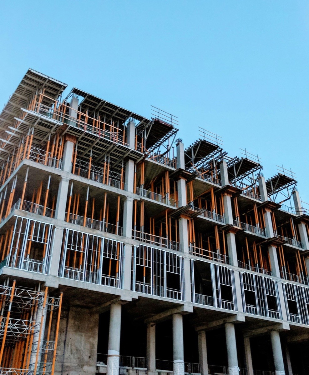 A multi-storey concrete frame under construction, still propped floor by floor